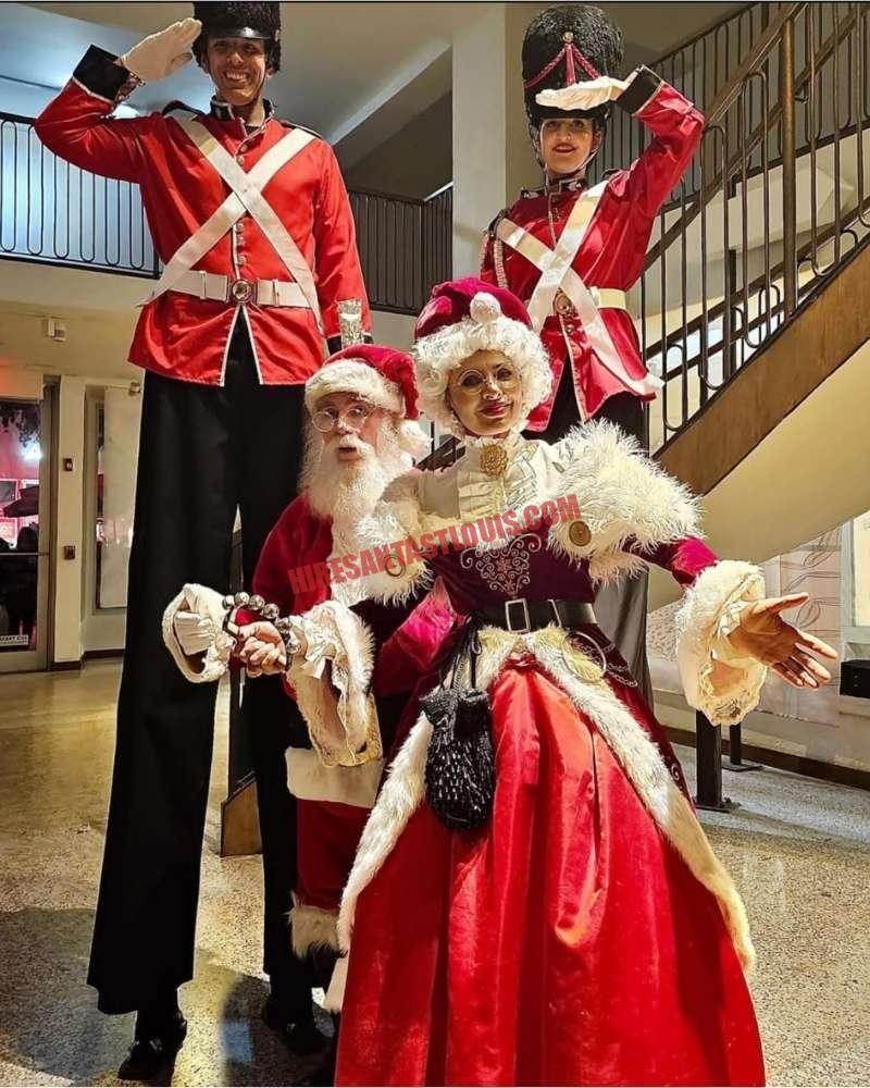Hire Santa for a company Christmas party in St. Louis: Santa, Mrs. Claus, and two stilt nutcrackers indoors.