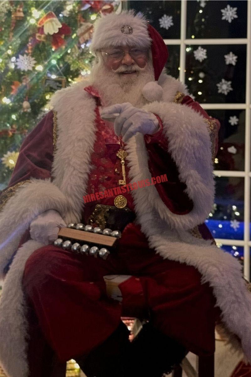 Santa for hire in St. Charles, MO: Santa seated with sleigh bells and a gold key by a night window.